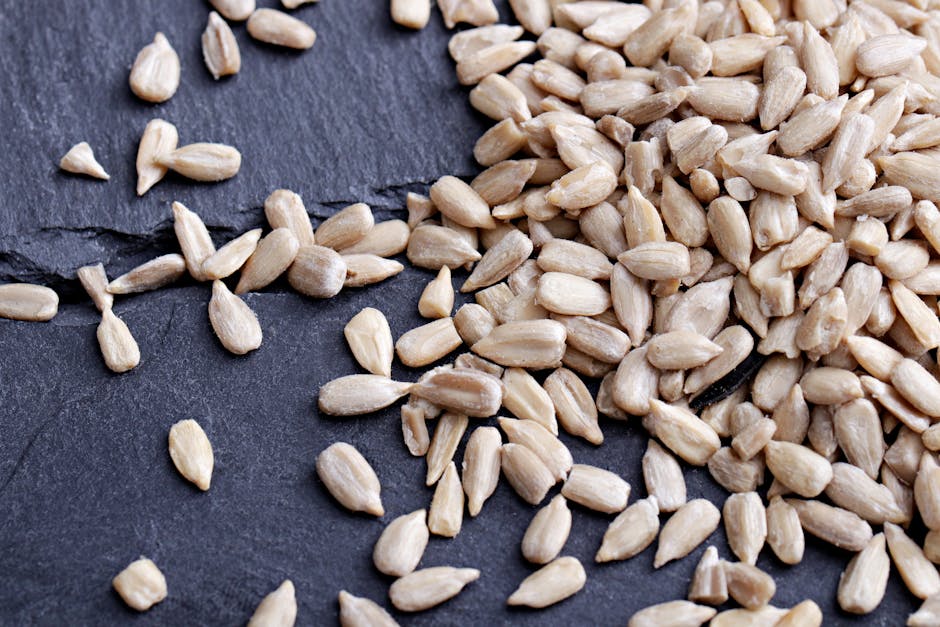 A detailed close-up image of organic sunflower seeds scattered on a slate surface, highlighting texture and freshness.